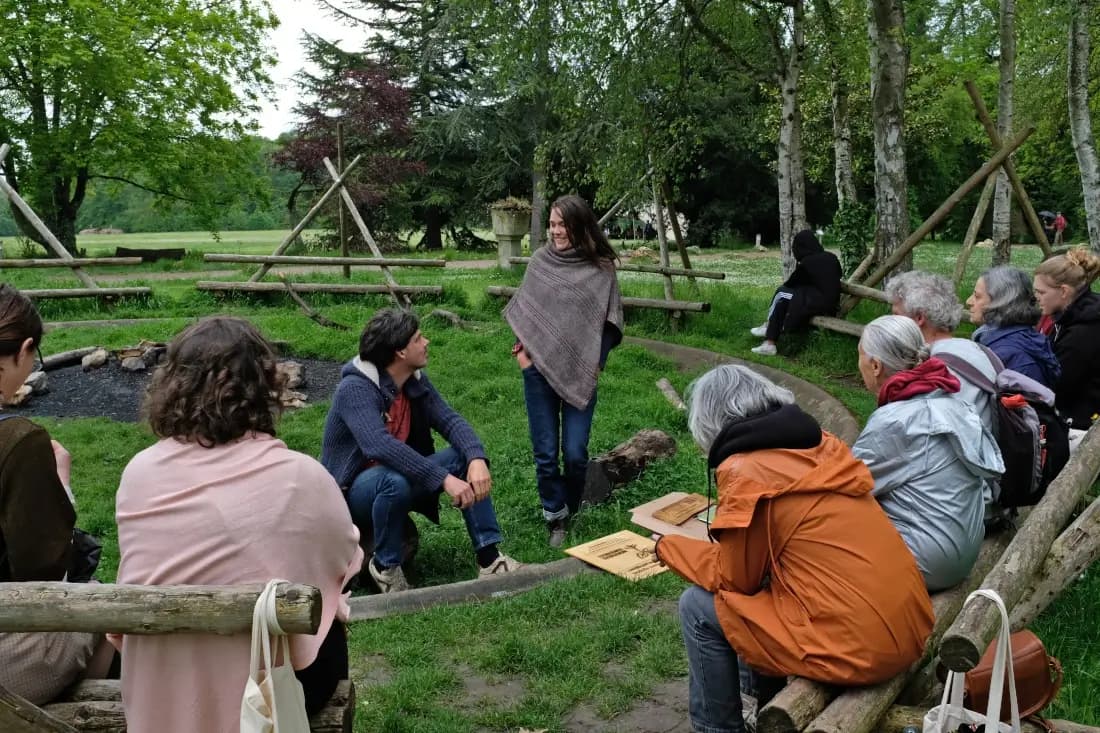 Groupe de personnes réunies en cercle dans un jardin, partageant un moment d'échange au sein de l'association
